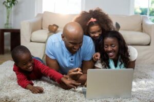 Family-Buying-Life-Insurance-Online1-300x200 A family in their living room, smiling, looking at a laptop