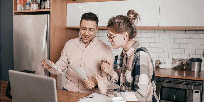 Couple-deciding-on-life-insurance-options-1-700x350 A couple, having a discussion while looking at a laptop and paper documents