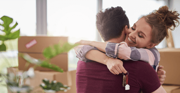 home-buyers-Completion A young couple hugging, holding the keys to their new home