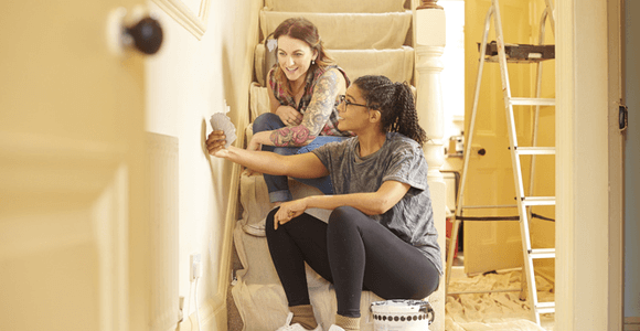 A young couple, deciding on paint colours for a wall in their new home