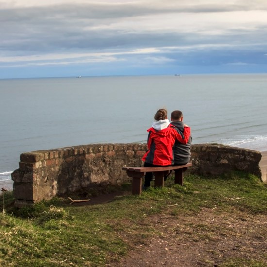 People sitting on a bench looking out to sea