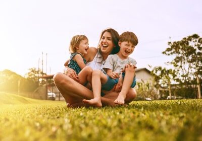 Stock_Family laughing_400x298 Mother and two children sitting on grass