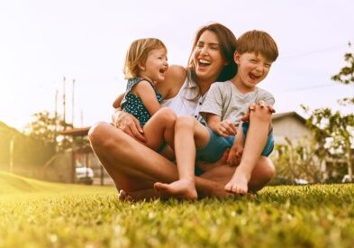 Stock_Family laughing_550x275 Mother and two children sitting on the grass